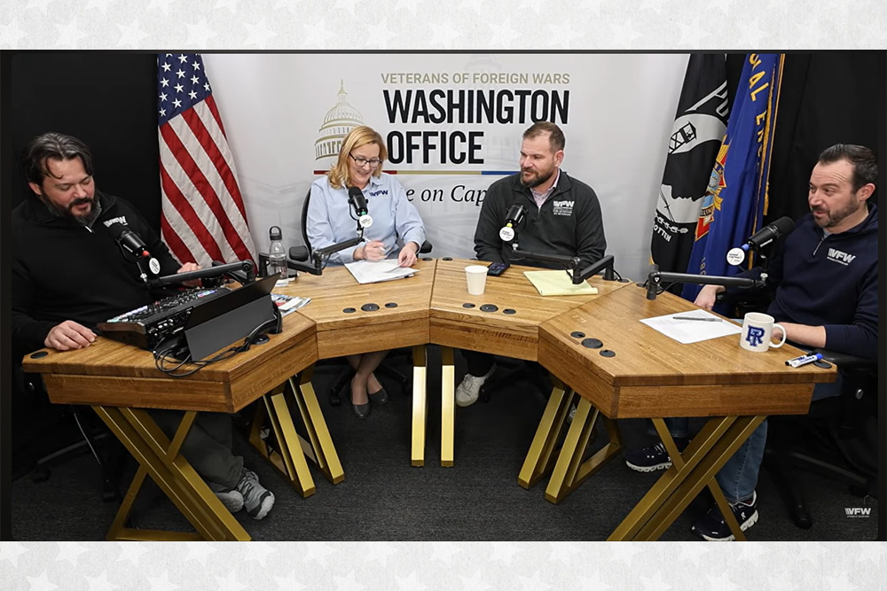 VFW staff sit in front of microphones at a table with a sign hanging behind them that reads Veterans of Foreign Wars Washington Office.