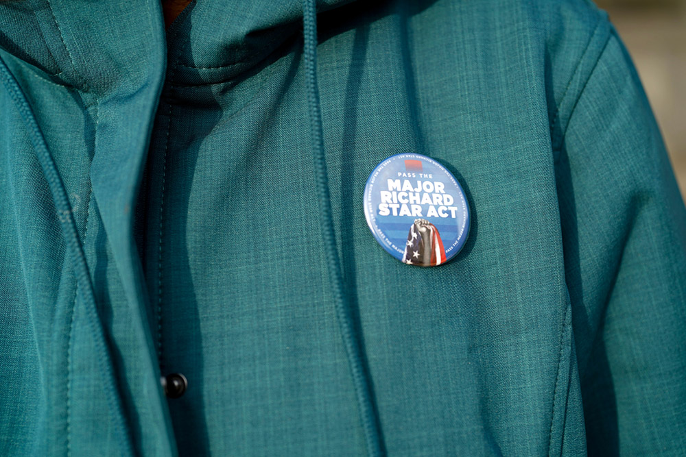 Close-up of a jacket with a round button that reads “Pass the Major Richard Star Act.”