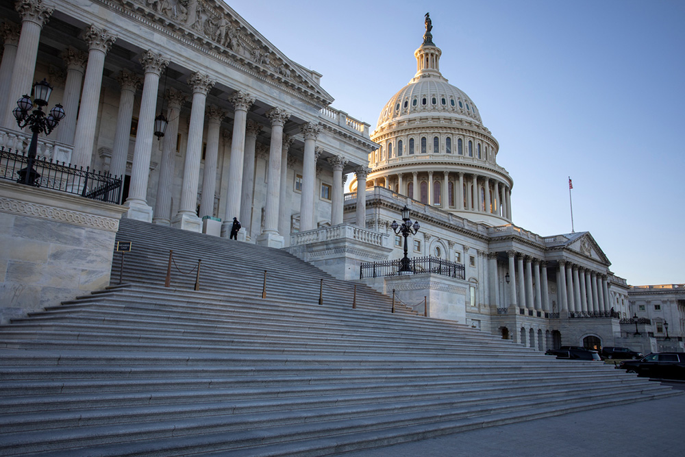 The U.S. Capitol building with its dome and columns rises above wide stone steps in daylight.
