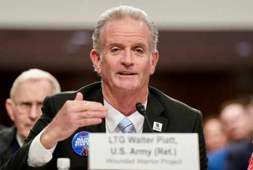 Walt Piatt speaking at a congressional hearing, gesturing while seated behind a microphone, with a name placard reading “LTG Walter Piatt, U.S. Army (Ret.) — Wounded Warrior Project.”